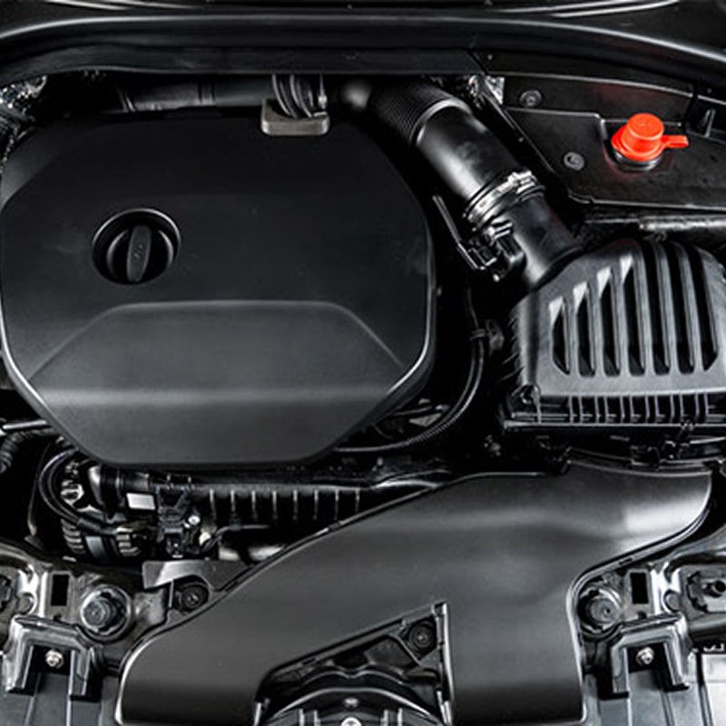 Compartiment moteur de voiture moderne, avec cache moteur noir, boîtier de filtre à air, prise d'air et capuchon rouge.